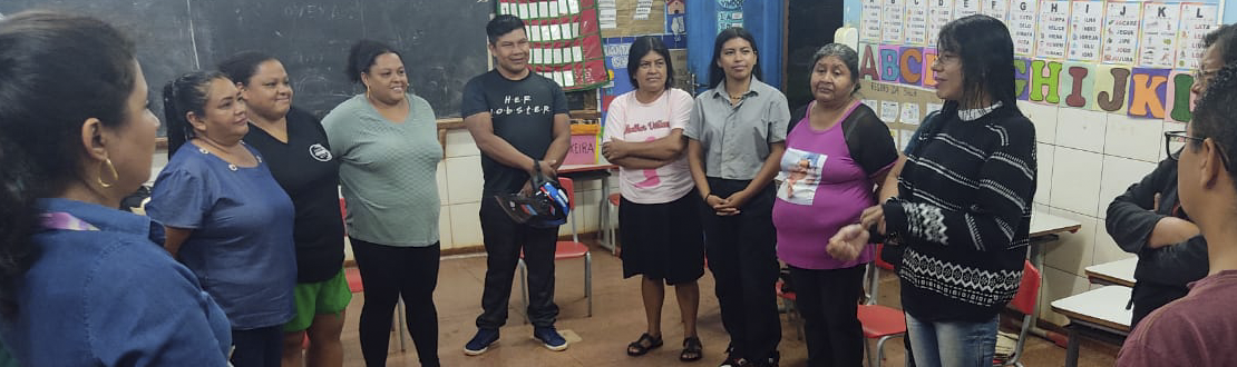 Foto de um grupo de mulheres e homens em pé no interior de uma sala de aula.