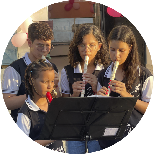 Foto de um grupo de crianças tocando flautas em frente ao Instituto Dom de Deus.