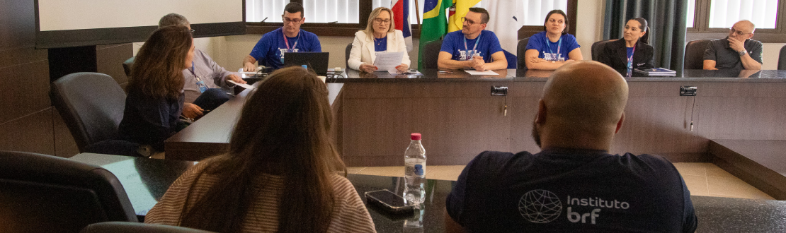 Foto tirada durante a reunião do Instituto BRF com representantes da UNIVATES. A sala tem uma mesa em formato de “u” e as pessoas estão sentadas ao redor.