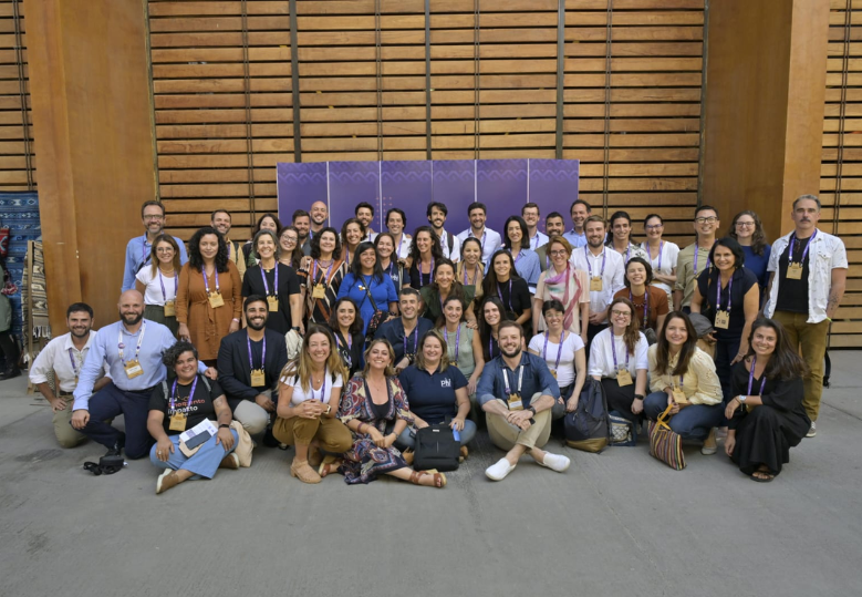 Foto de um grupo diverso de pessoas, algumas em pé e outras sentadas, que estiveram no evento.