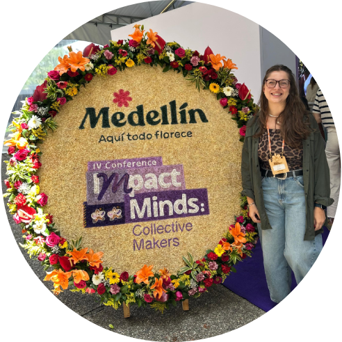 Foto posada de Gabriele Candido ao lado de um painel do evento com flores em sua borda.