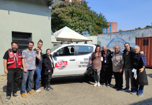 Foto de Caique com um grupo de pessoas ao redor de um carro da Ação Cidadania. 