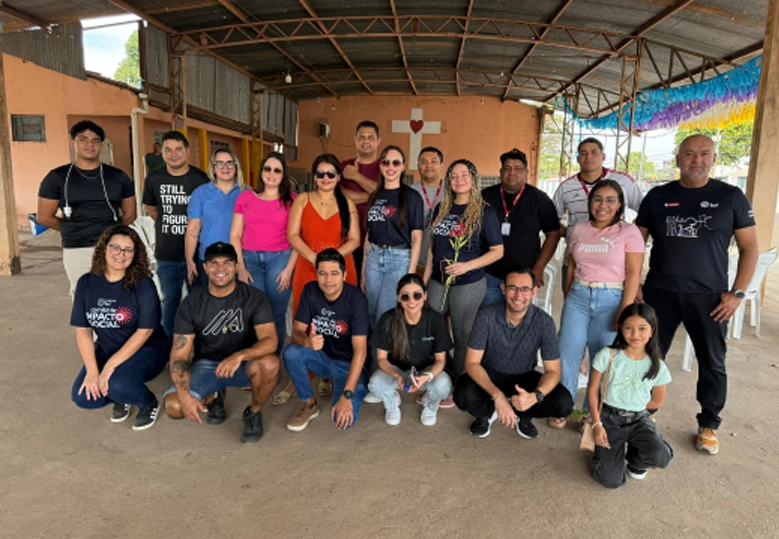 Foto posada do grupo de pessoas, algumas em pé e outras abaixadas, em uma área externa.