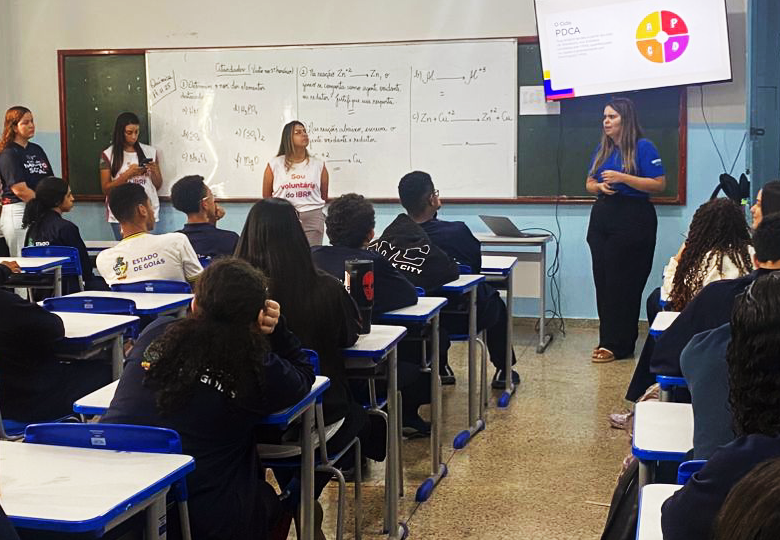 Foto de jovens participantes reunidos em sala de aula durante atividade de 5S e PDCA, com apoio de voluntários do Instituto.