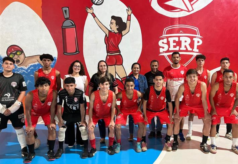 Foto de um grupo de meninos e representantes do Instituto MBRF e da SERP posicionados em uma quadra. Alguns estão abaixados e com as mãos nos joelhos, enquanto o restante do grupo está em pé.