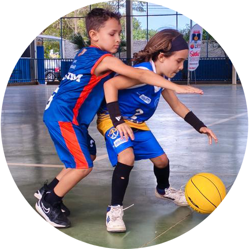 Foto de um menino tentando roubar a bola de basquete de outro.