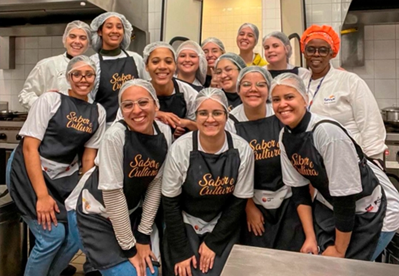 Foto de um grupo diverso de mulheres usando toucas e posando sorridentes lado a lado.