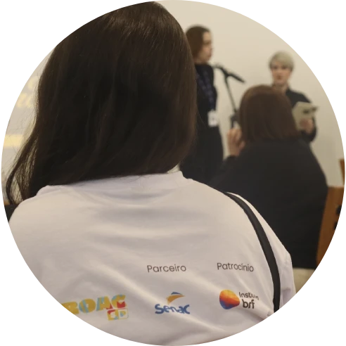 Foto de uma das alunas de costas. Ela usa uma camiseta com os logos do Instituto MBRF e Senac.