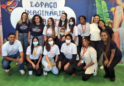Foto do grupo de voluntárias e voluntários em frente ao backdrop do Espaço Imaginário Marisa Monte.