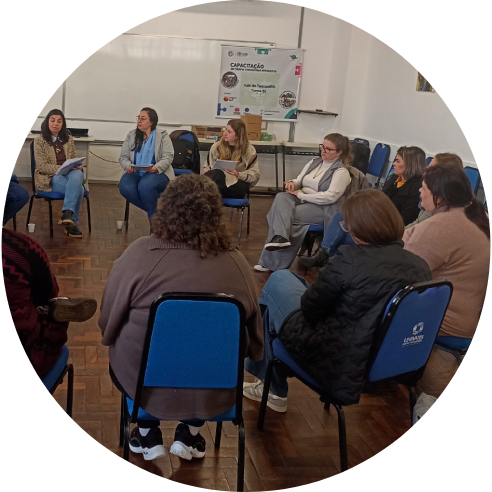 Foto de uma das turmas da TCI dentro de uma sala de aula sentadas em um círculo.